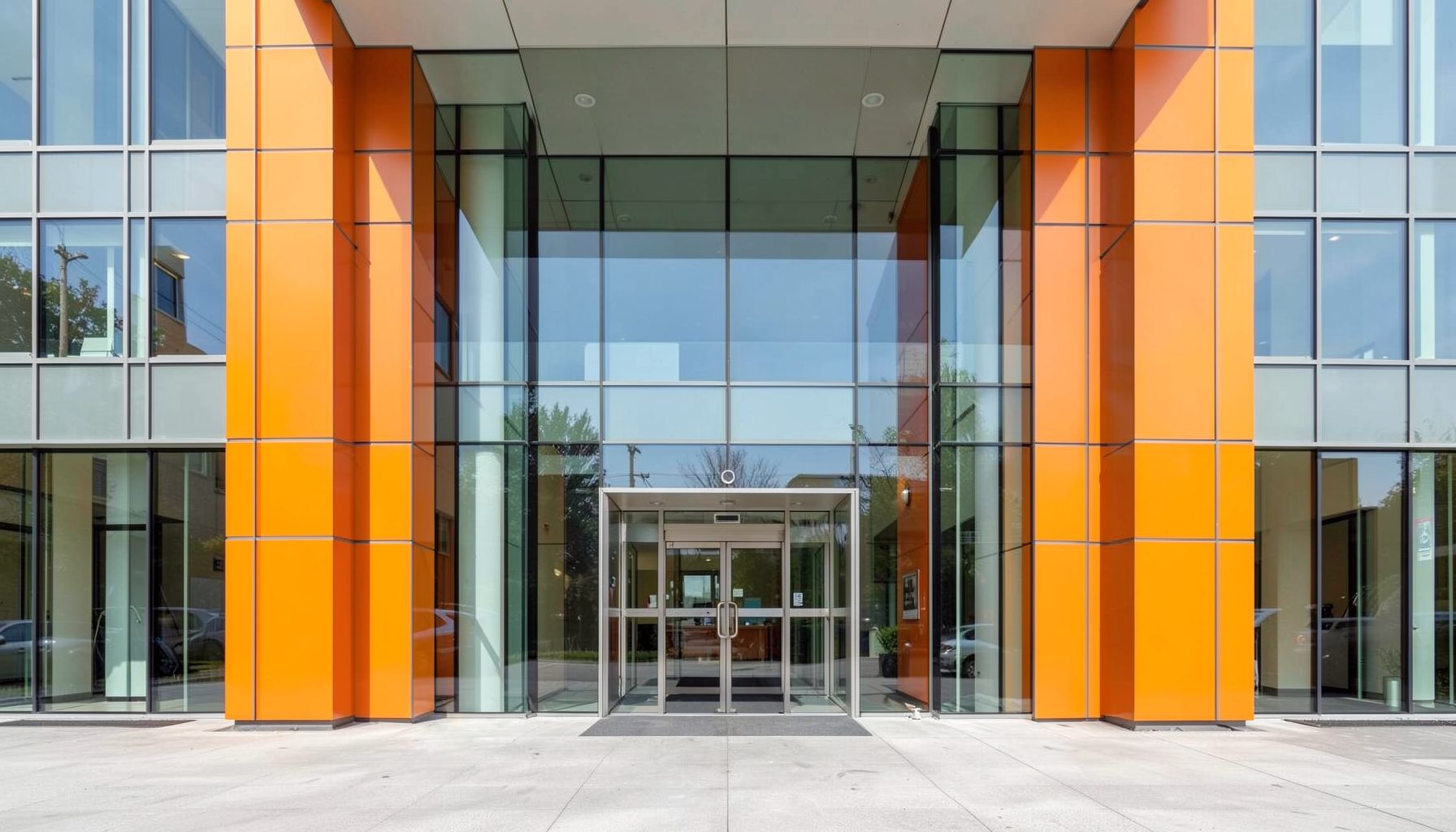 Clean architectural photograph of a modern medical building entrance with strong symmetry, glass panels, and bright welcoming light