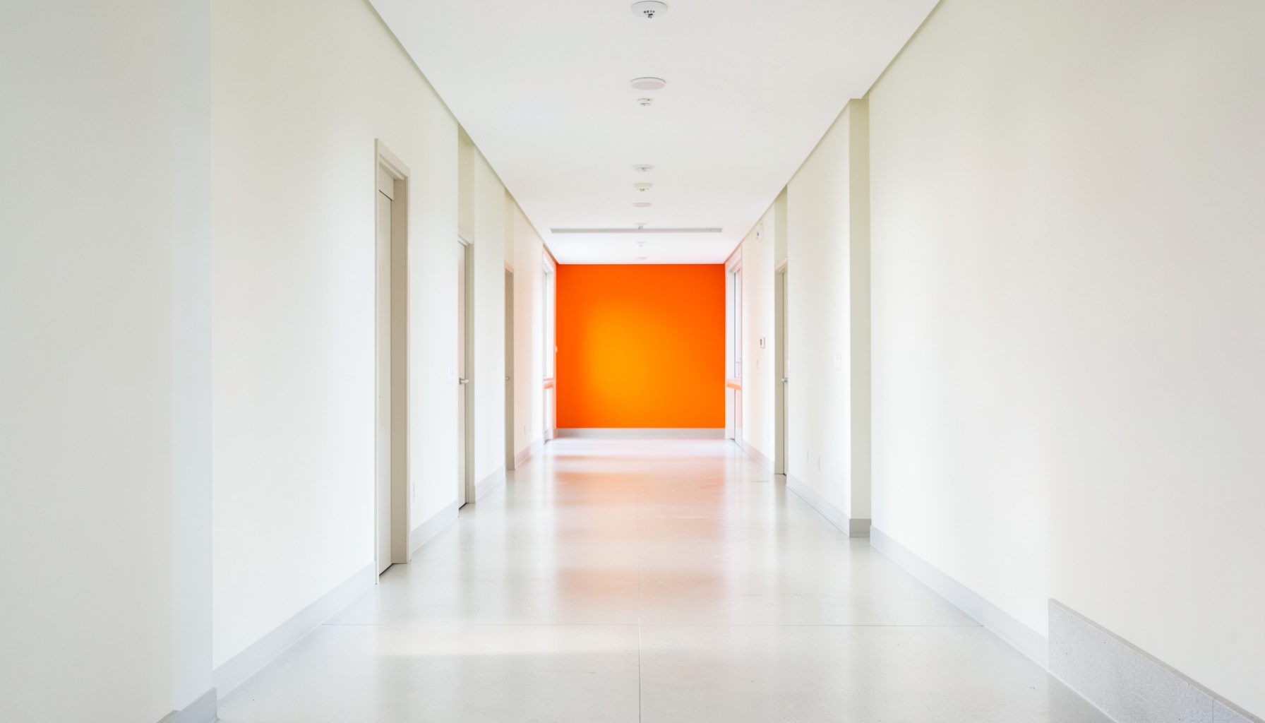 Clean, bright healthcare corridor with soft natural light, pale walls, and a calm professional atmosphere